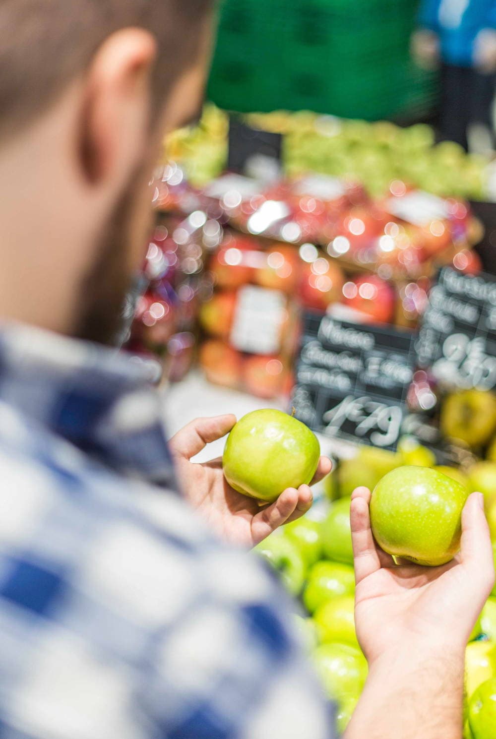 Guy comparing two green apples trying to make a choice