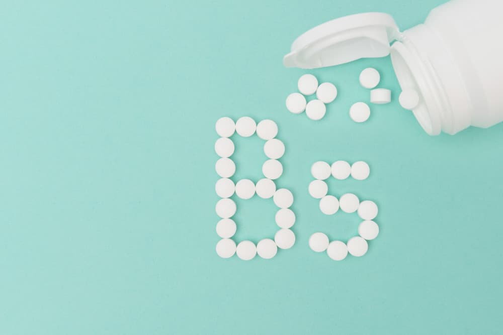 Pill bottle against a turquoise blue background with pills coming out of the bottle forming the shape 'B5'.